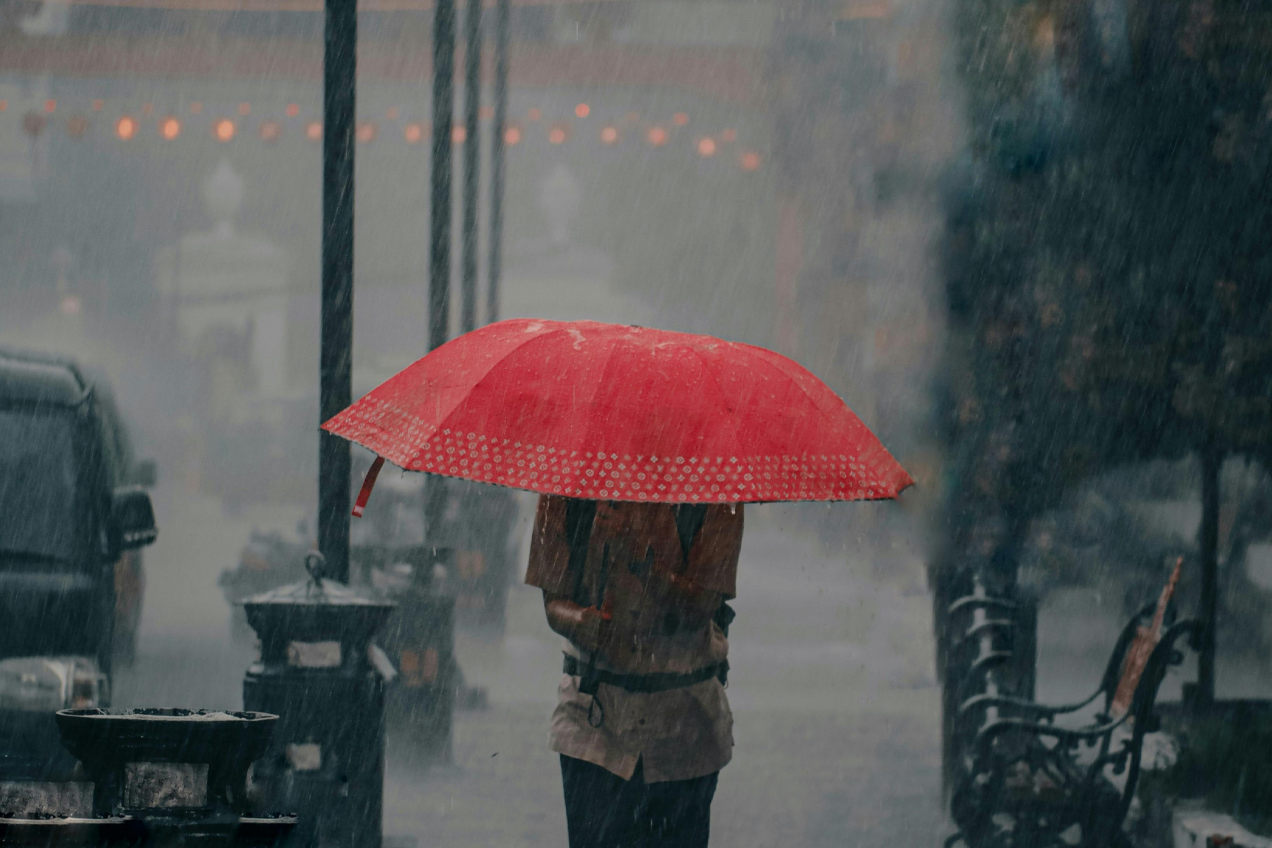 man with a red umbrella in a rainstorm
